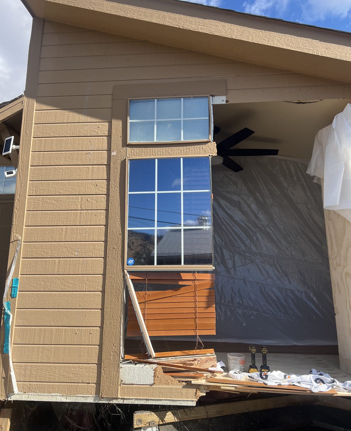 End wall of the manufactured home torn open by the impact, window hanging out